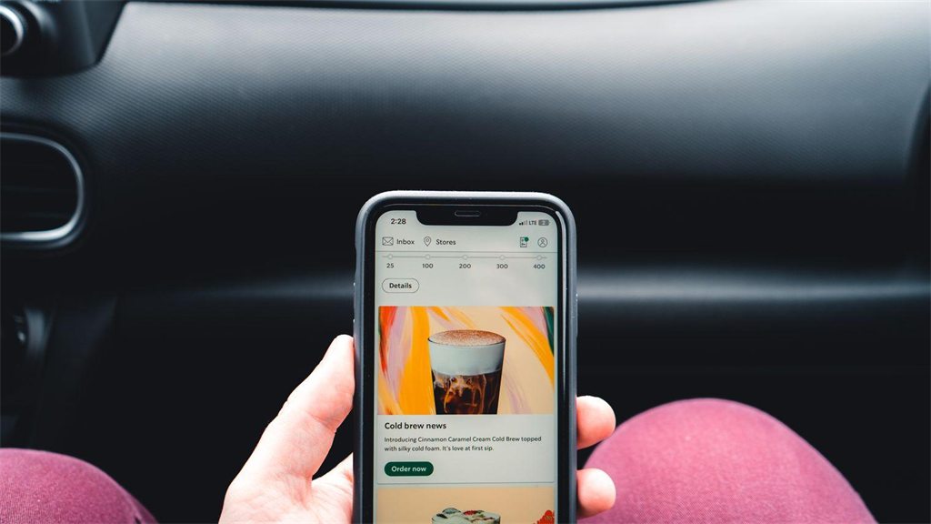 Mão segurando um celular com um aplicativo aberto dentro do carro