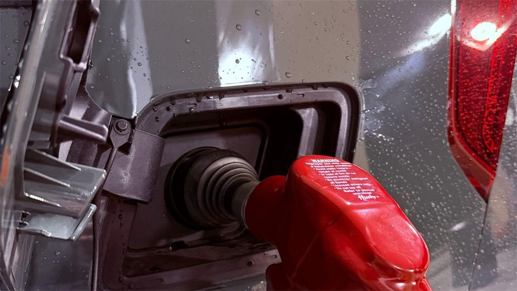 Bico de abastecimento vermelho encaixado no bocal de um carro
