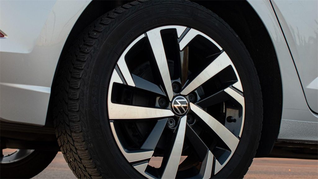 Roda e pneu dianteiros de um carro prata, vistos de perto