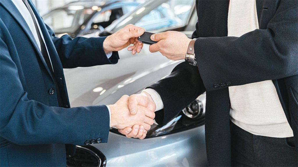 Dois homens apertando as mãos ao lado de um carro