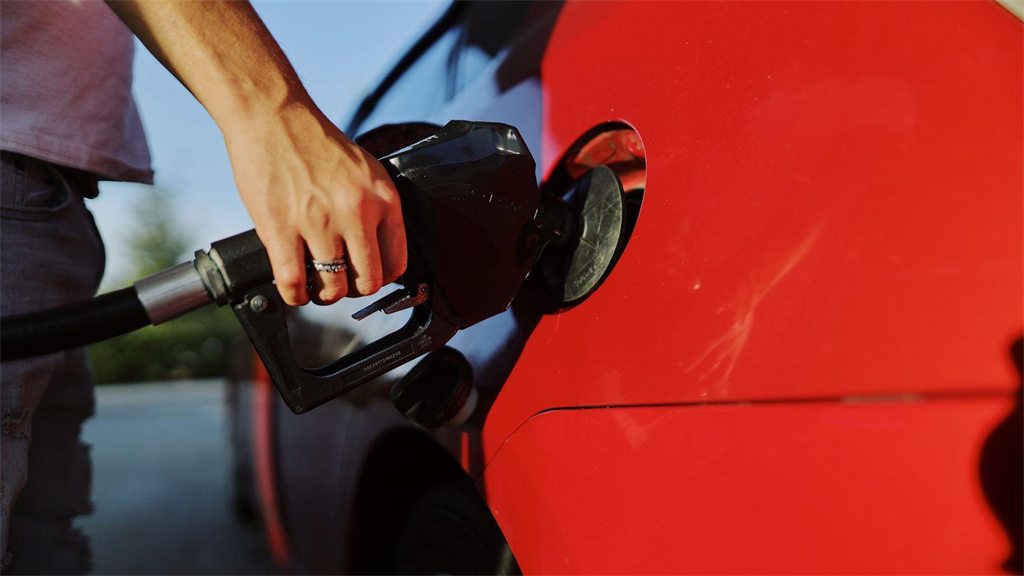 Bico de abastecimento encaixado no bocal de um carro vermelho