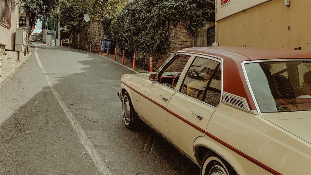 Carro antigo bege estacionado em rua de bairro