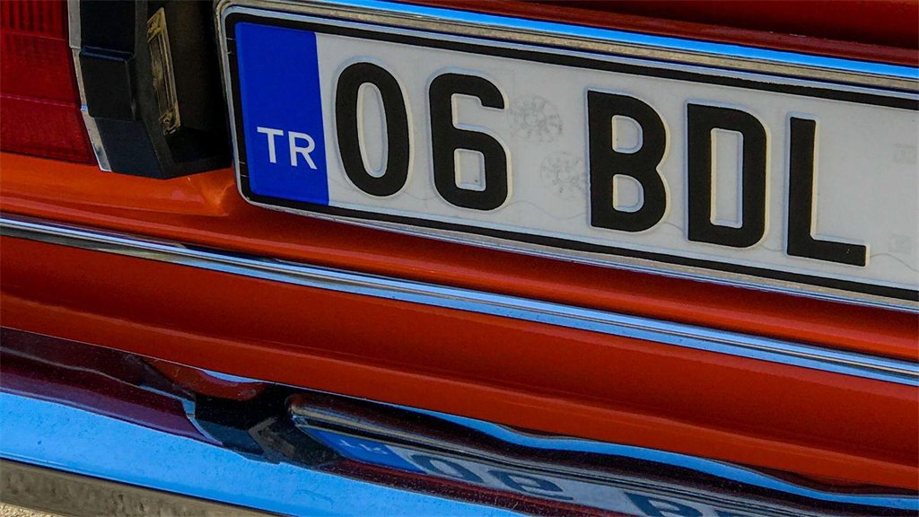 Placa de veículo em destaque na traseira de um carro vermelho