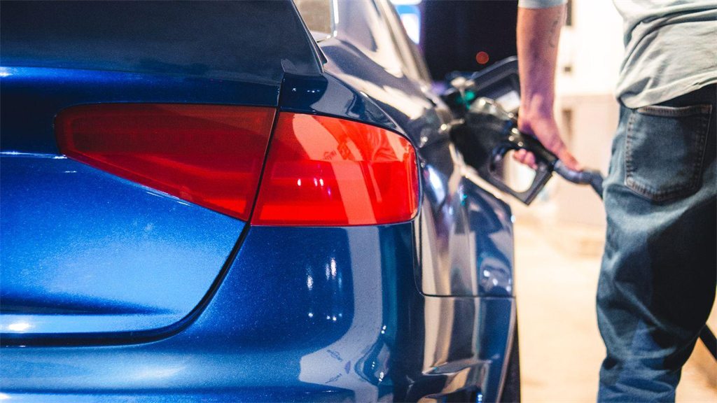 Bico de abastecimento verde encaixado no bocal de um carro azul