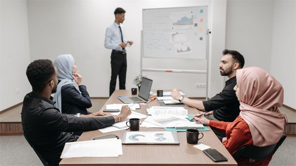 Reunião de trabalho em sala com quadro branco e participantes à mesa
