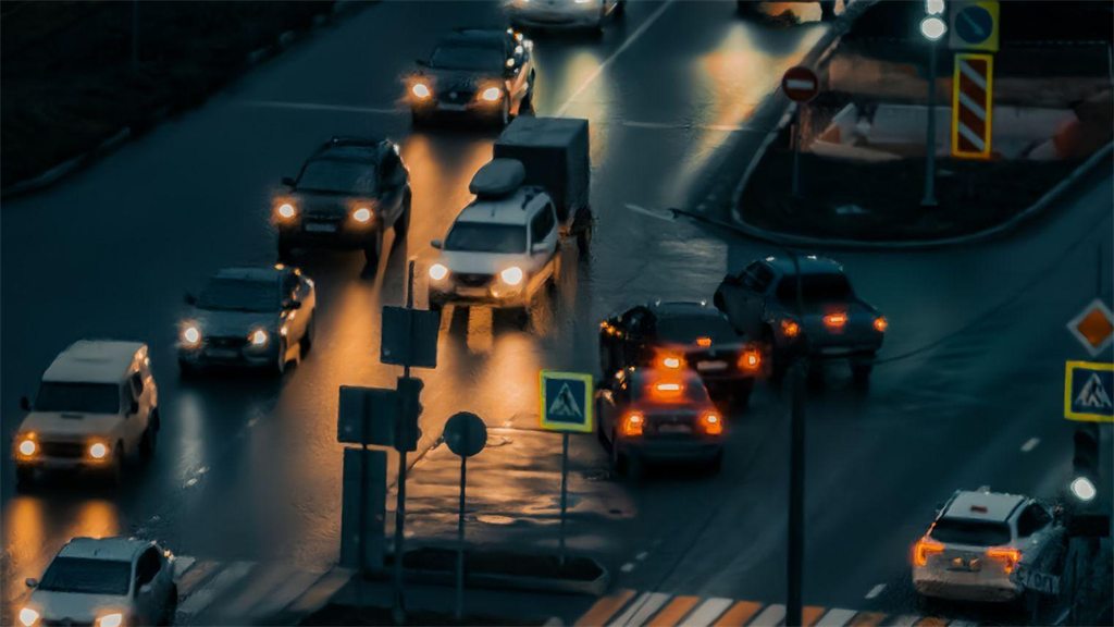 Trânsito noturno em avenida, com faróis e semáforos acesos