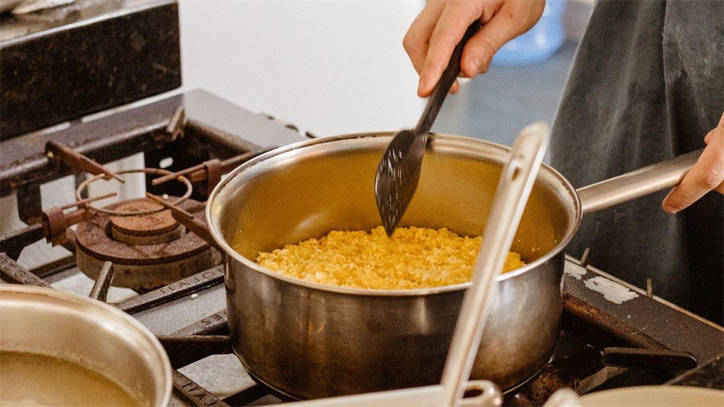 Panela no fogo com alimento sendo mexido por uma colher