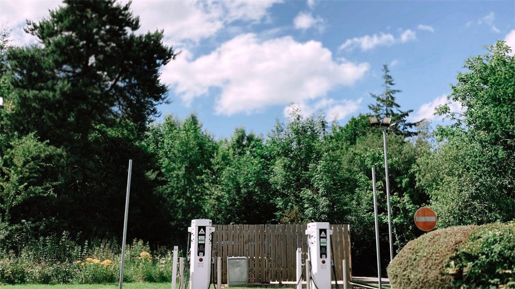 Estação de recarga de carros elétricos ao ar livre, cercada por árvores